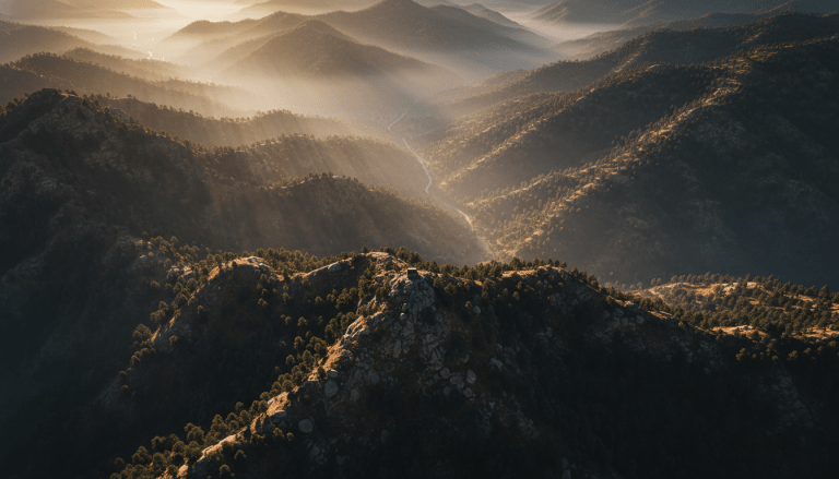 Paisaje montañoso y accidentado al amanecer, con valles brumosos y picos rocosos, simbolizando el terreno como un tablero de ajedrez estratégico para operaciones militares, seguridad y planificación de emboscadas. Vistas aéreas detalladas de la topografía natural.