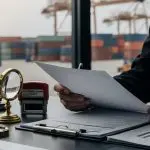 Investigador analizando documentos y sellos aduaneros para detectar violaciones en las leyes de importación y exportación.
