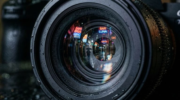 Primer plano de lente de cámara de videovigilancia profesional con reflejo de callejón nocturno, simbolizando la óptica de seguridad.
